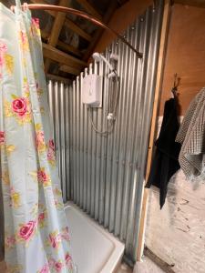 a shower curtain with flowers on it in a bathroom at Orchard Shepherds Hut in Calstock