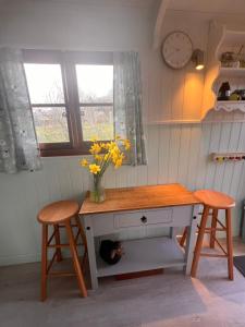a table with two stools and a cat sleeping under it at Orchard Shepherds Hut in Calstock +5 photos