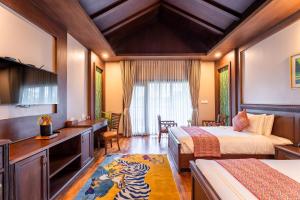 a hotel room with two beds and a television at River Bank Jungle Resort, Chitwan in Chitwan
