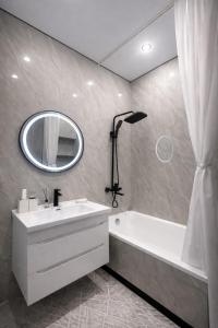 a bathroom with a sink and a tub and a mirror at Современный апартамент Tandau в центре in Almaty +5 photos