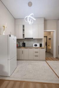 a kitchen with white cabinets and a white refrigerator at Современный апартамент Tandau в центре in Almaty