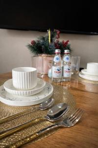 a table with plates and spoons and bottles of water at Современный апартамент Tandau в центре in Almaty