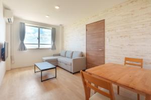 a living room with a couch and a table at コート エトワレ マエザト-新築アパートメントホテル- in Ishigaki Island +53 photos