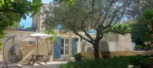 a patio with a table and an umbrella and a house at Maison jardin grande piscine 2 étoiles in Marseille