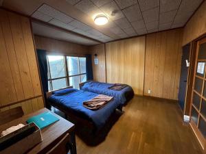 a room with two beds and a table in it at Denim-yado Ken-健- in Tamano