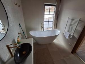 a bathroom with a white tub and a sink at Merino vendégház in Tiszabecs
