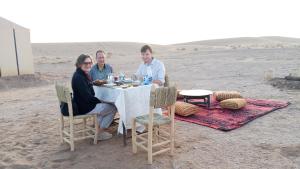 a group of people sitting at a table in the desert at Iriki Desert Camp Foum Zguid in Foum Zguid