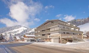a large building with a parking lot in the snow at REMIND Apartements Brixental in Brixen im Thale +22 photos