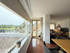 a living room with a table and chairs and a large window at Secret Spot Apartment - Quinta da Barca in Esposende