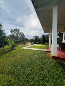 a view from the porch of a house with a grass yard at Flora Lake View Resort Wilpattu in Wilpattu