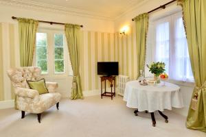 a living room with a table and a chair and a television at Llangattock Park House in Crickhowell