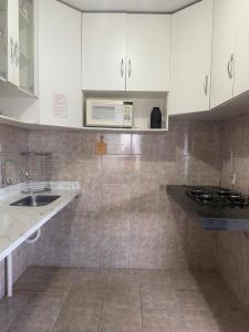 a kitchen with a sink and a microwave at Pousada da Vânia in Vespasiano