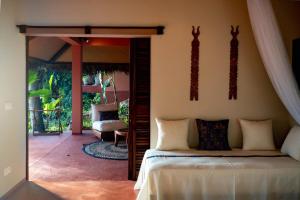 a bedroom with a bed and a door to a patio at Jardin Vanille in Anjiabe