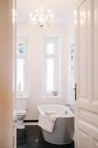 a bathroom with a tub and a toilet and a chandelier at Golf Apartment Villa Elisabeth in Mariánské Lázně +105 photos
