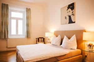 a bedroom with a bed with white sheets and a window at Golf Apartment Villa Elisabeth in Mariánské Lázně