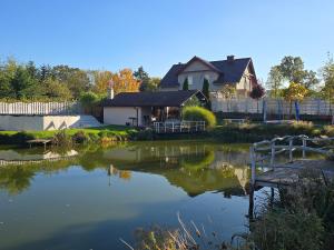 a house with a pond in front of a house at Agroturystyka Nad Stawem in Sulęcin
