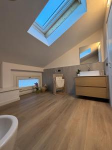 a bathroom with a skylight and a tub and a sink at Beato Mario Apartments in Tirano