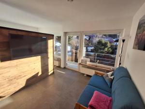 a living room with a blue couch and a large flat screen tv at Spatz am Joch in Oberjoch