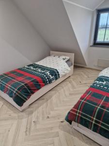 a bedroom with two beds and a wooden floor at Apartamenty Szepty Mazur in Odoje