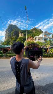 a man standing on the side of the road holding a hat at Bee Backpackers Hostel in Quang Binh