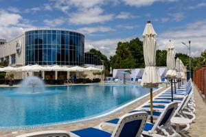 a pool with lounge chairs and umbrellas in front of a hotel at Grand-Marine Hotel & SPA in Odesa