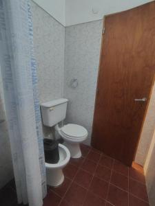 a bathroom with a toilet and a wooden door at Cabaña Quimey in Villa Rumipal +18 photos
