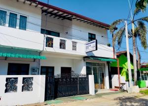 a white building with a palm tree in front of it at Chrish Residence in Negombo