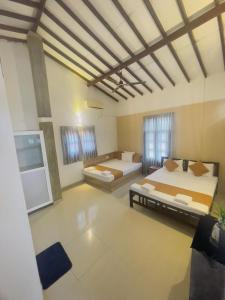 a large room with two beds and two windows at Chrish Residence in Negombo