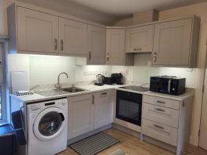 a kitchen with white cabinets and a washing machine at Village View in Adare