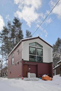 a small house in the snow with trees at Hakuba Caesar in Hakuba