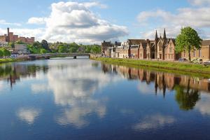 a river in a city with buildings and a bridge at Inverness Ardtower Escapes in Culloden