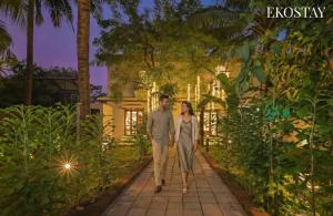 a man and a woman walking through a garden at night at EKOSTAY - Serenity Villa in Alibaug