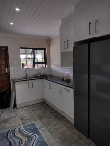 a kitchen with white cabinets and a black refrigerator at Zebra Lodge in Gqeberha