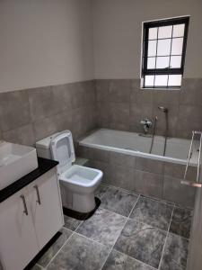 a bathroom with a toilet and a tub and a sink at Zebra Lodge in Gqeberha +7 photos