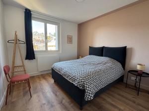 a bedroom with a bed and a window and a chair at La pause Tulliste in Tulle