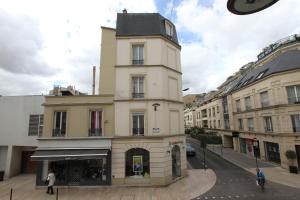 a tall building with a clock tower on a street at Rempart du Chateau-SV82 StudioVincennes in Vincennes