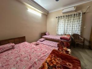 a bedroom with two beds and a window at Sudama Bhavan in mayapur
