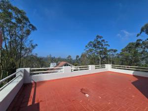 a balcony with a brick floor and white railing at Guru Villa in Yercaud +9 photos