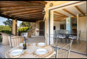 a patio with a table and chairs and a kitchen at Orsa sul mare a Baja Sardinia in Cala Bitta