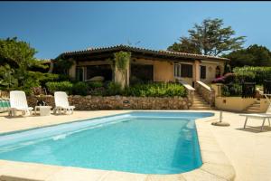 a swimming pool with two chairs and a house at Orsa sul mare a Baja Sardinia in Cala Bitta