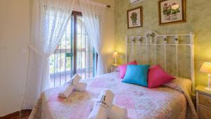 a bedroom with a bed with colorful pillows and a window at Villa La Cola Nerja by Ruralidays in Nerja +26 photos