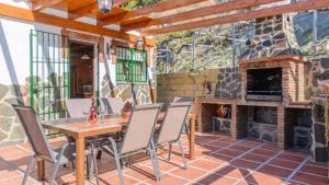a patio with a table and chairs and a stone fireplace at Villa La Cola Nerja by Ruralidays in Nerja