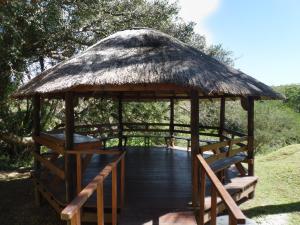 a wooden gazebo with benches and a thatched roof at HAPPY JUNGLE at 6 in St Lucia