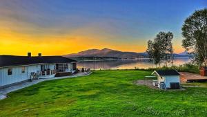 a house on the shore of a lake at sunset at Apartment in Senja in Senja