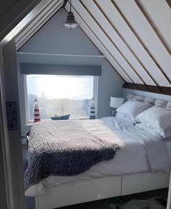 a bedroom with a bed and a window with a lighthouse at Lifeboat House in Skerries