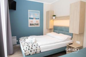 a bedroom with a bed with a blue wall at SOLEO Family Resort - domki w Rewalu 3 min od Morza - 3 Baseny, 5 Jacuzzi, Sauna, ANIMACJE, Małpi Gaj, 3 Sale Zabaw, 4 Place Zabaw, 2 Restauracje in Rewal