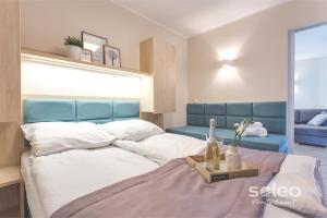 a bedroom with a large bed and a blue couch at SOLEO Family Resort - domki w Rewalu 3 min od Morza - 3 Baseny, 5 Jacuzzi, Sauna, ANIMACJE, Małpi Gaj, 3 Sale Zabaw, 4 Place Zabaw, 2 Restauracje in Rewal
