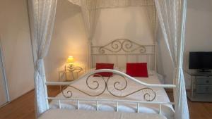 a bedroom with a white canopy bed with red pillows at Gîte de groupe La Chapinière 7 min ZooParc Beauval in Châteauvieux +35 photos