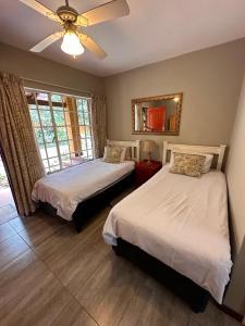 a bedroom with two beds and a mirror at Roosters Nest BnB in Midrand