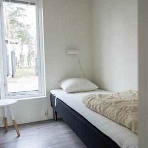a bed sitting in a room with a window at Kapelludden Camping & Stugor in Borgholm +22 photos